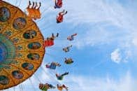 Colorful swing ride at an amusement park with people enjoying a thrilling day under the clear blue sky.