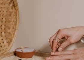 Hands raking a small zen rock garden with sand and stones, promoting relaxation and mindfulness.