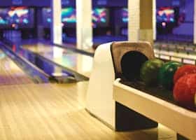 Colorful bowling balls lined up in a modern alley, ready for a thrilling game night.