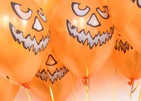 Orange balloons with jack-o'-lantern faces for Halloween celebration.