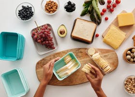 Top view of preparing a healthy lunch with fruits, cheese, and crackers, showcasing fresh ingredients and a vibrant lifestyle.