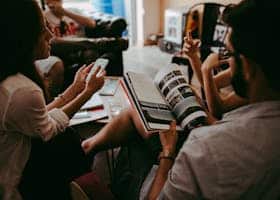 Casual group discussion with people reading a magazine and interacting indoors.