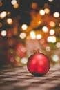Vibrant red Christmas ornament with bokeh background, perfect for holiday promotions.
